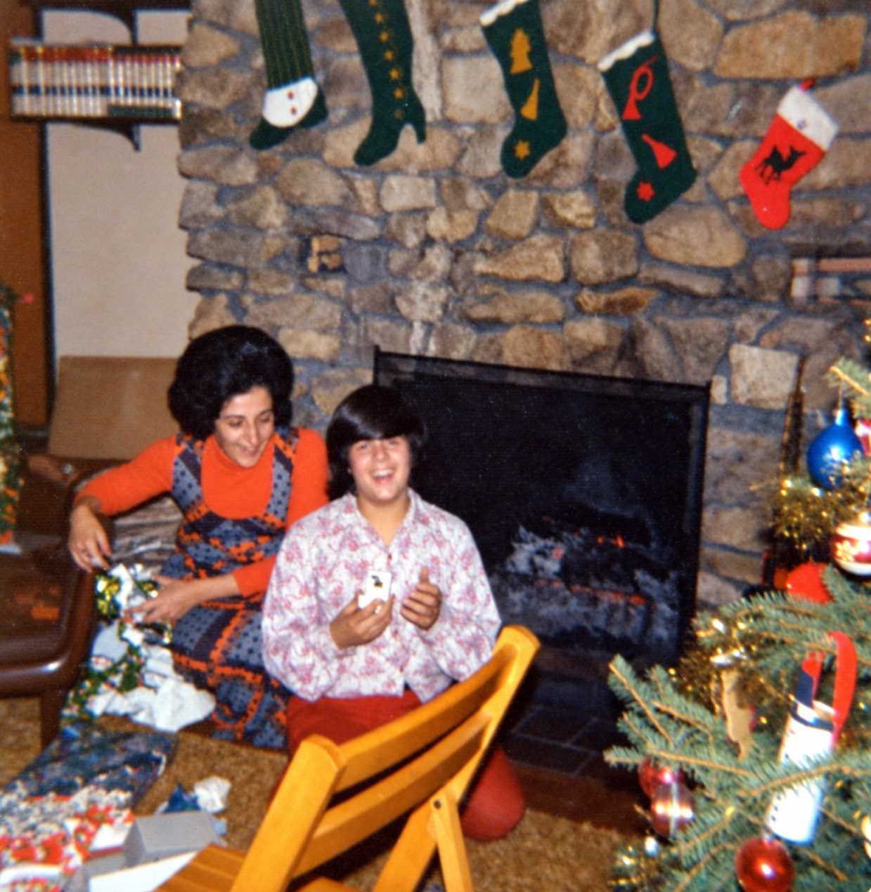 Family Christmas gifts beside a stone fireplace and Christmas tree